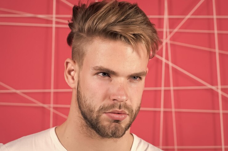 Foto homem com cerdas em estrito rosto concentrado fundo rosa conceito de masculinidade cara barbudo e atraente com penteado homem com barba ou cara não barbeado parece bonito e bem arrumado
