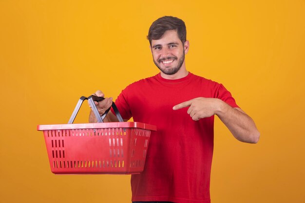 Homem com cesta de supermercado em fundo amarelo