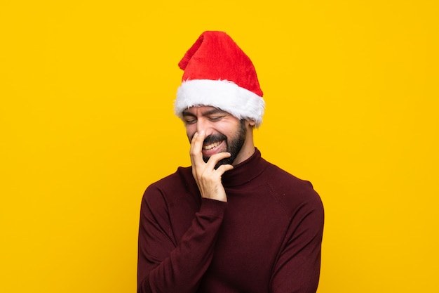 Homem com chapéu de Natal isolado muro amarelo sorrindo muito