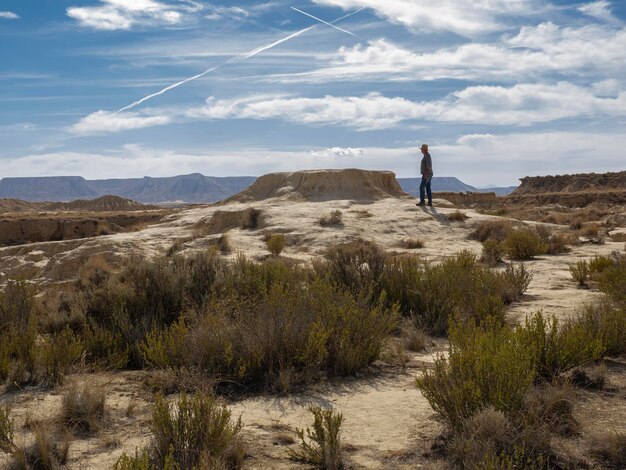 Foto homem com chapéu no deserto olhando para o infinito sob o céu azul bardenas reales navarra espanha