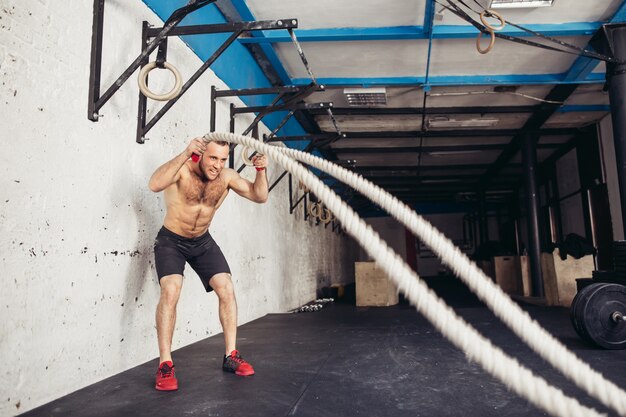 Homem com cordas de batalha exercitando no ginásio de fitness