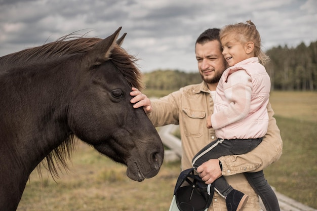 Homem com criança se comunica com cavalo