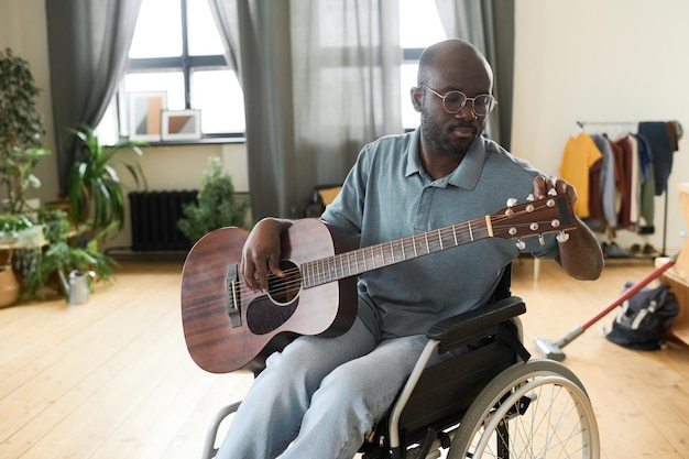 Homem com deficiência afinando uma guitarra para tocar