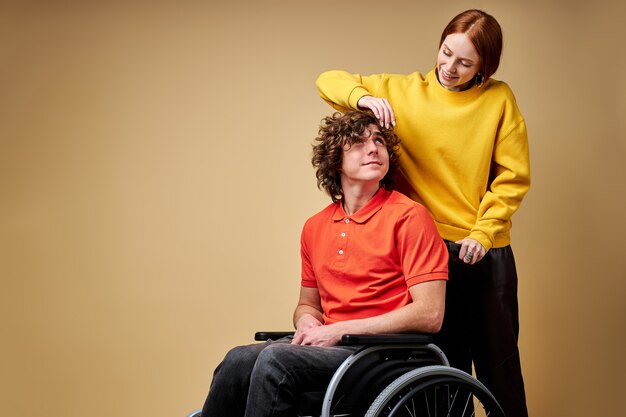 Homem com deficiência, aproveitando o tempo sua linda namorada gentil, cuidando dele tocando seu cabelo.