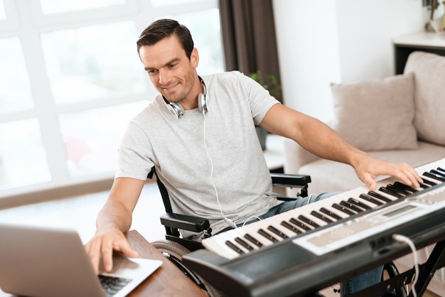 Foto homem com deficiência compondo música com piano elétrico.