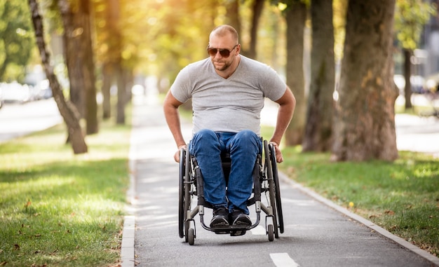 Homem com deficiência em cadeira de rodas caminhando no beco do parque