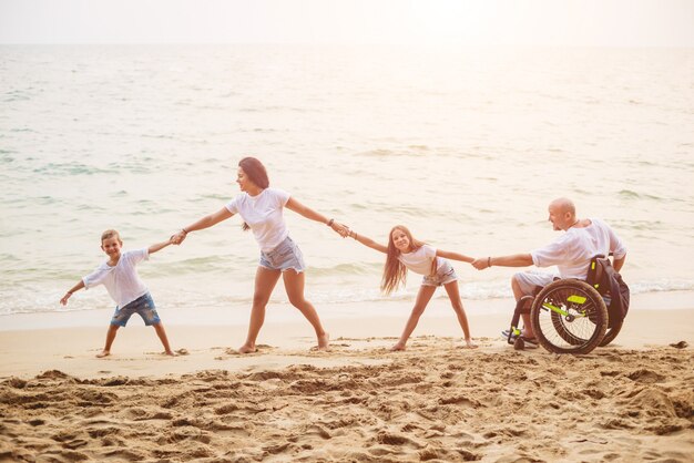 Homem com deficiência em cadeira de rodas com sua família na praia.