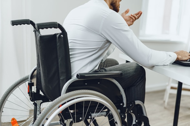 Homem com deficiência em cadeira de rodas usando laptop close-up