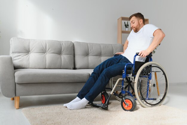 Homem com deficiência em casa tenta ficar de pé em uma cadeira de rodas O conceito de reabilitação após lesões e acidentes de carro