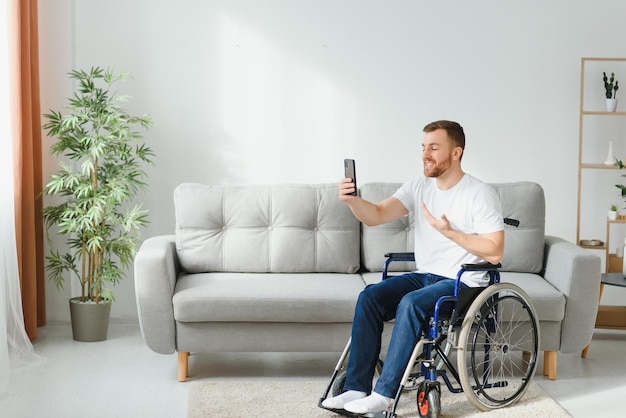 Homem com deficiência usando smartphone moderno para conversa por vídeo enquanto fica em casa Conceito de deficiência e tecnologia de pessoas