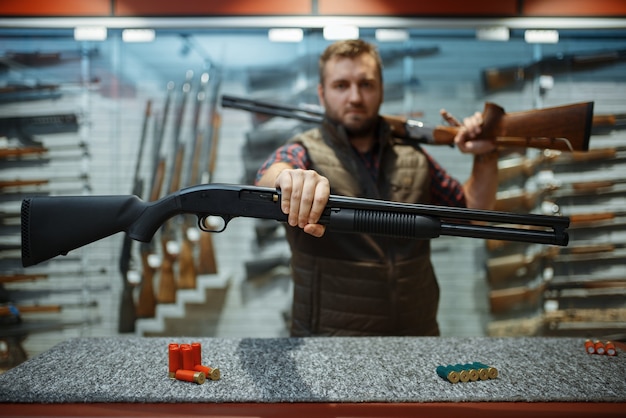 Foto homem com dois rifles no balcão da loja de armas