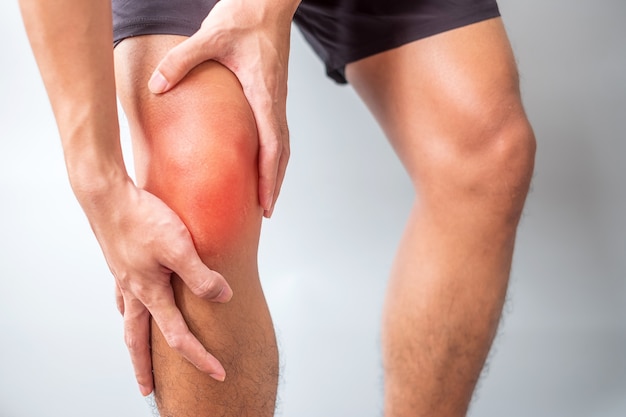 Homem com dores musculares em fundo cinza. Idosos têm dor no joelho devido ao joelho de corredor ou síndrome da dor patelofemoral, osteoartrite, artrite, reumatismo e tendinite patelar. conceito médico