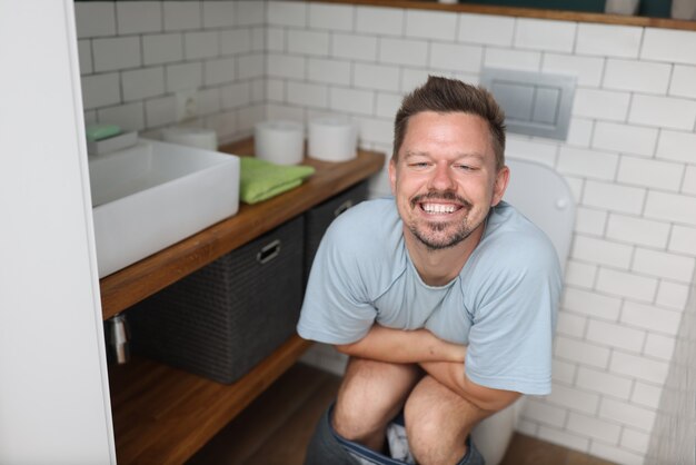 Homem com emoção de alívio sentado no banheiro