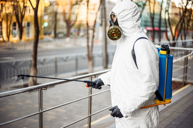 Foto homem com equipamento de proteção desinfetando a cidade