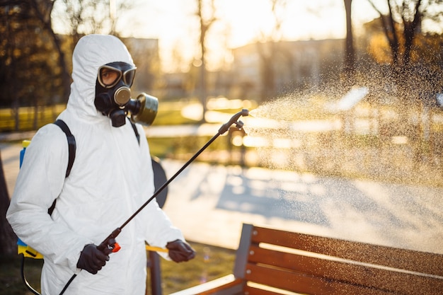 Homem com equipamento de proteção desinfetando a cidade