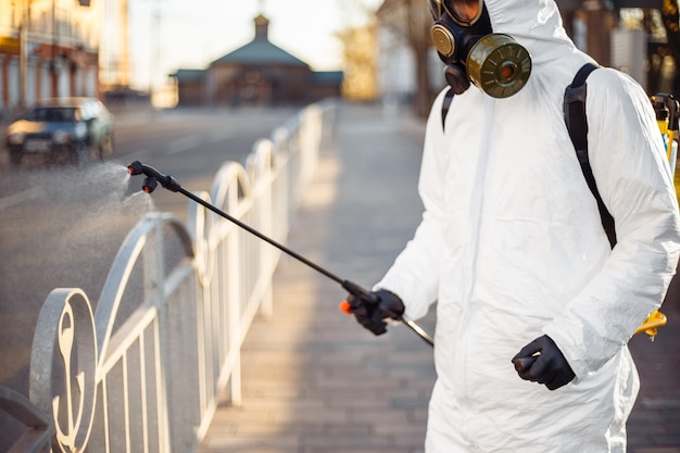 Foto homem com equipamento de proteção desinfetando a cidade