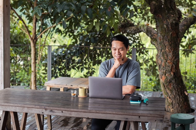 Homem com expressão sorridente procurando um laptop para reunião online ou streaming de vídeo