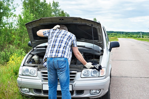 Homem com ferramentas perto de carro quebrado