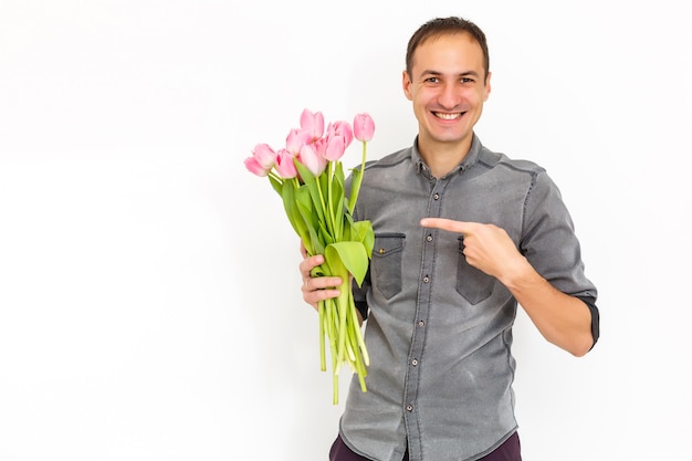 Homem com flores. Homem romântico com buquê de tulipas para aniversário. Feliz Dia da Mulher. Dando buquê de flores. Homem bonito, dando flores. Fundo branco. Foto horizontal.