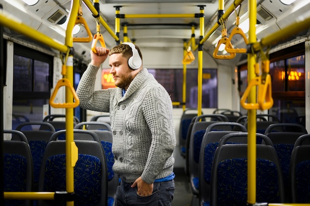 Homem com fones de ouvido, passando por transportes públicos