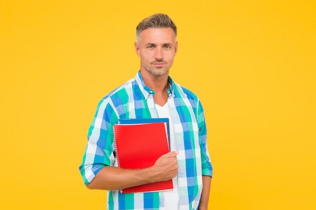 Homem com fundo de pasta amarela. Empresário segurar o livro para anotações. cara tem bloco de notas para escrever. bonito professor de escola ou universidade. adulto homem estudante segurando notebooks. Inspirado para trabalhar duro.