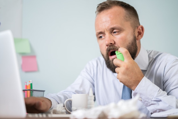 Homem com gripe trabalhando no escritório