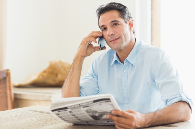 Homem, com, jornal, usando, cellphone, em, cozinha