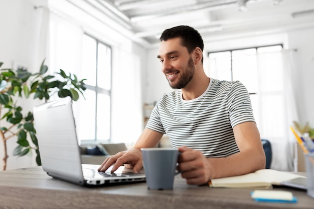 homem com laptop a beber café no escritório em casa