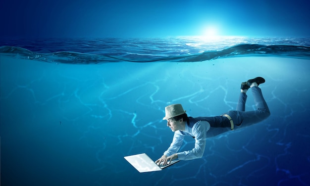Homem com laptop debaixo d'água. Mídia mista