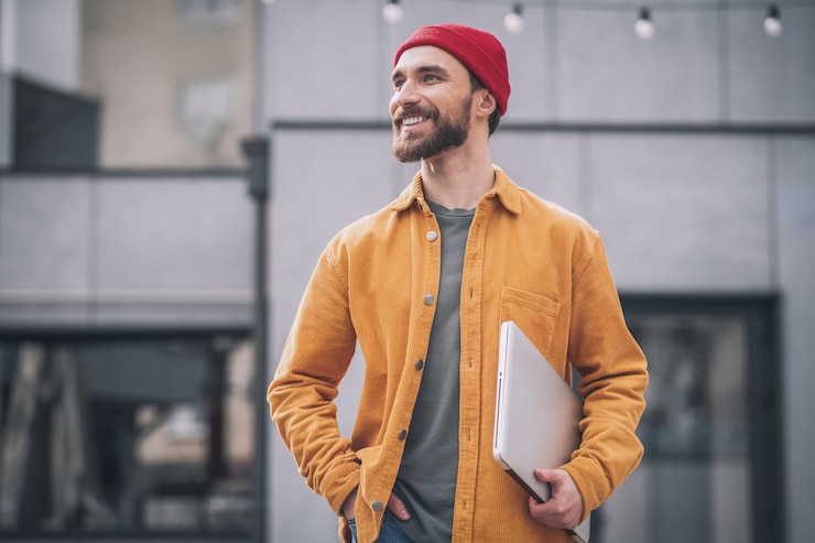 Foto homem com laptop. jovem barbudo com um chapéu vermelho e um laptop