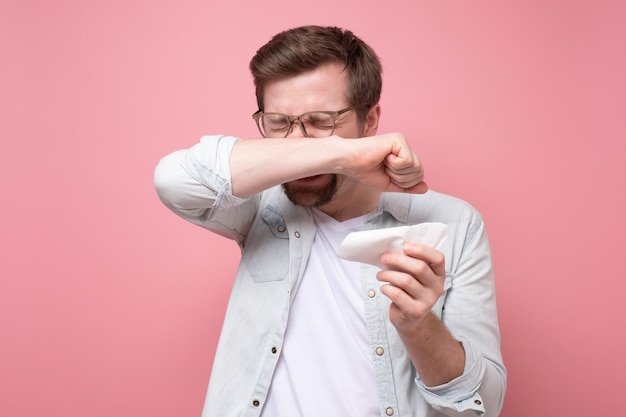 Homem com lenço e óculos espirrando doente ou com alergia