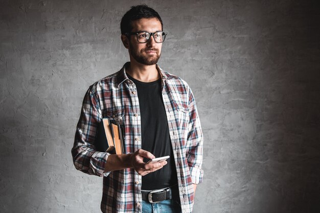 Homem com livros e olhando para a tela de um smartphone. Conceito de educação