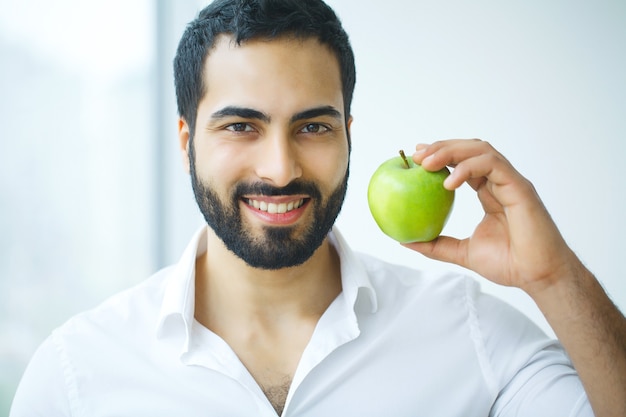 Homem com maçã. belo macho com sorriso branco, dentes saudáveis. imagem de alta resolução.