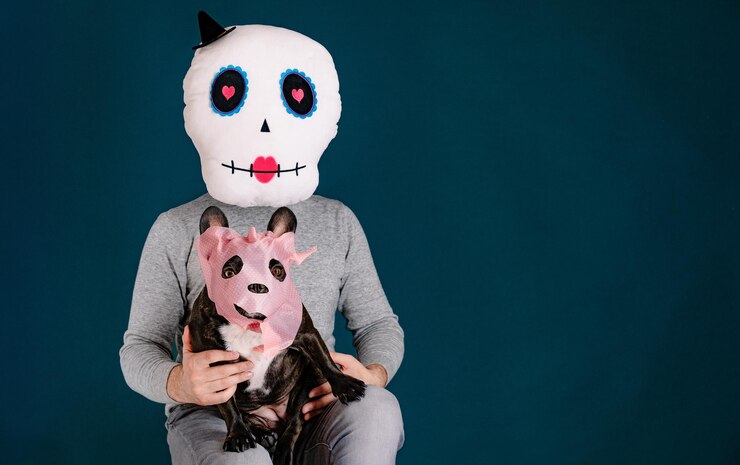 Foto homem com máscara de halloween segurando cão budog francês mascarado contra fundo azul