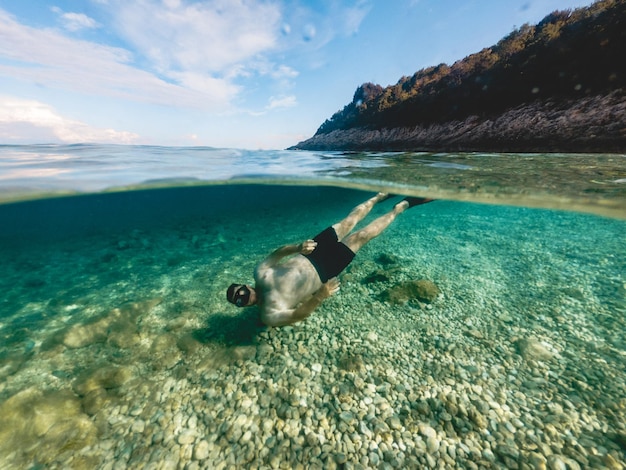 Homem com máscara de mergulho fazendo snorkel na água do mar, férias na Grécia