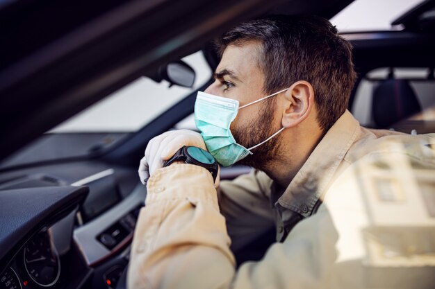 Homem com máscara e luvas, dirigindo um carro. Prevenção de infecções e controle de epidemia. Pandemia mundial. Fique seguro.
