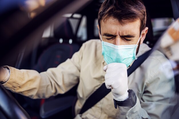 Homem com máscara e luvas dirigindo um carro tossindo. Prevenção de infecções e controle de epidemia. Pandemia mundial. Fique seguro.