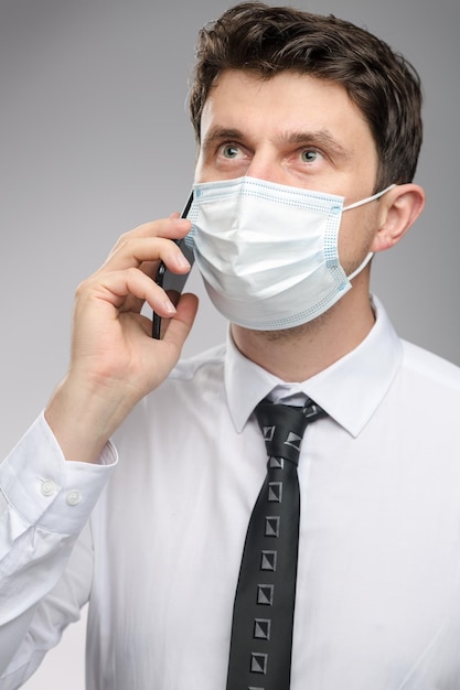 Homem com máscara facial conversando com cliente por telefone Trabalhador de escritório com máscara facial protetora no Coronavirus