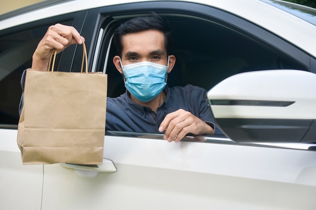 Homem com máscara facial sentado em um carro