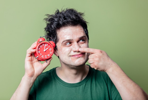 Homem com máscara limpa e despertador vermelho