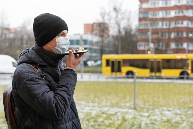 Foto homem com máscara médica falando ao telefone na cidade