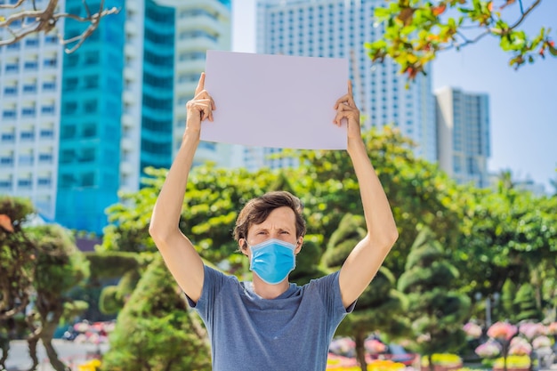 Homem com máscara médica previne doença de coronavírus segura um pôster para inscrições gratuitas COPIAR ESPAÇO