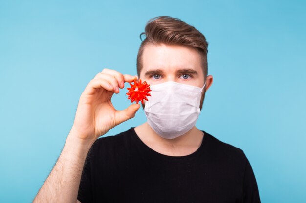 Homem com máscara médica segurando uma bola vermelha cobiçosa