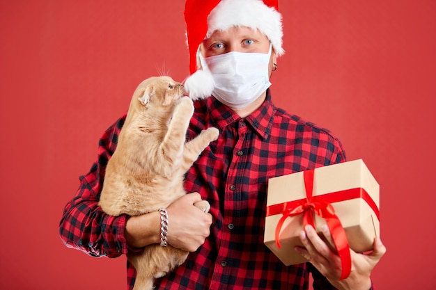 Homem com máscara protetora e chapéu de papai noel com presente de natal diy