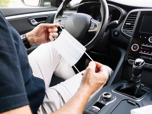 Foto homem com máscaras nas mãos dentro do carro