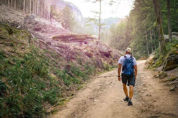 Homem com mochila caminhando pelo caminho de pedras na bela natureza