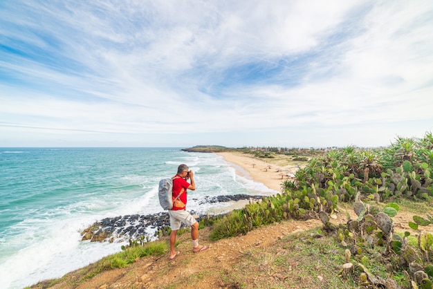 Homem com mochila, olhando para a costa tropical do penhasco acima. destino de viagem no vietnã, província de phu yen, entre da nang e nha trang. bai xep linda praia de areia