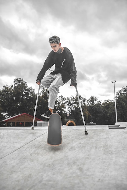 Foto homem com muletas no skate fazendo manobra na rampa