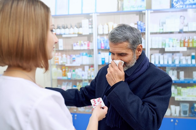 Homem com nariz entupido consultando farmacêutico feminino