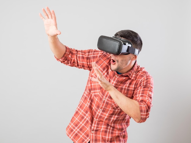 Homem com óculos de realidade virtual mostrando gesto isolado em um fundo cinza